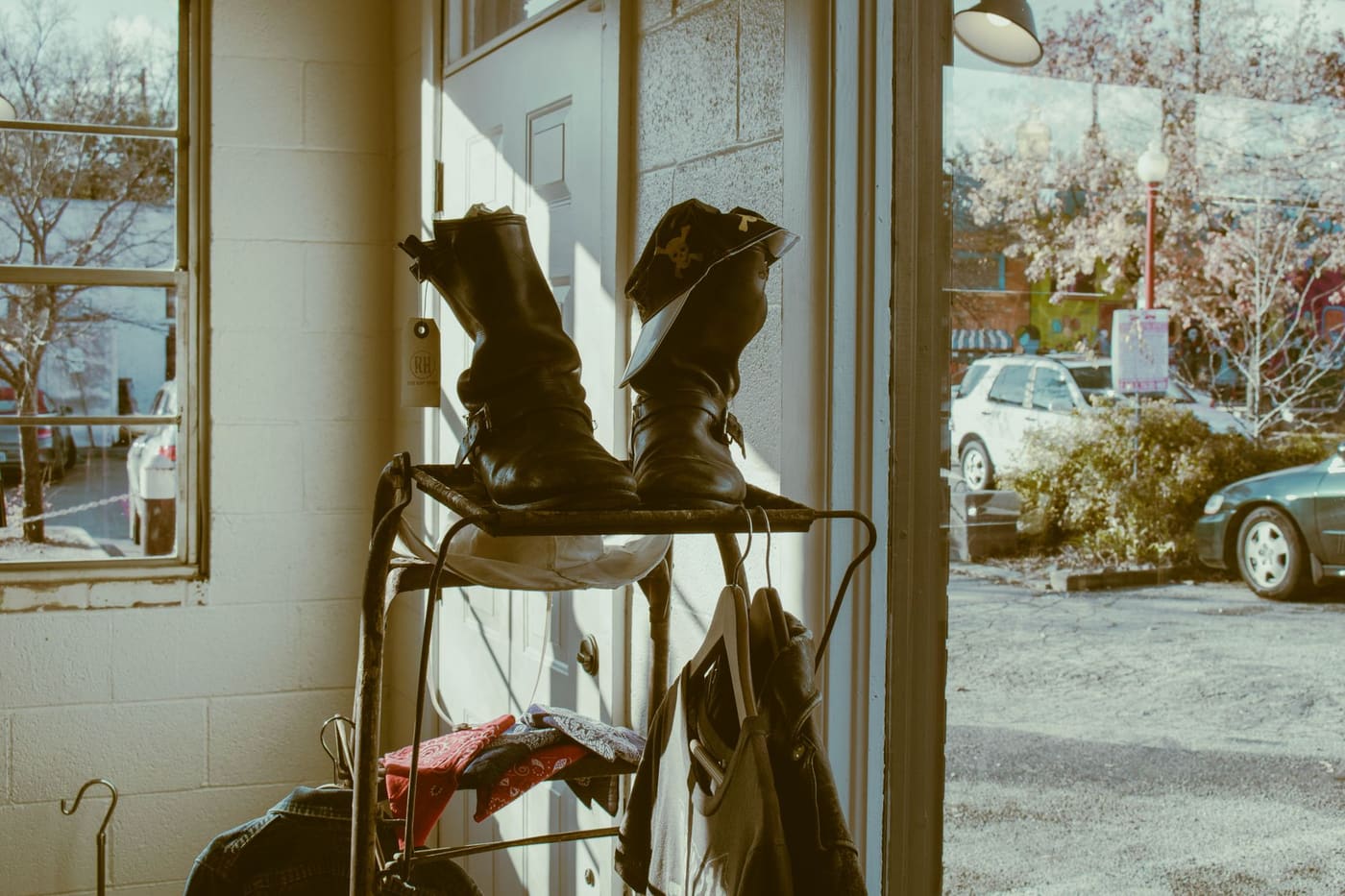 A pair of leather boots on a small metal rack beside a sunlit doorway